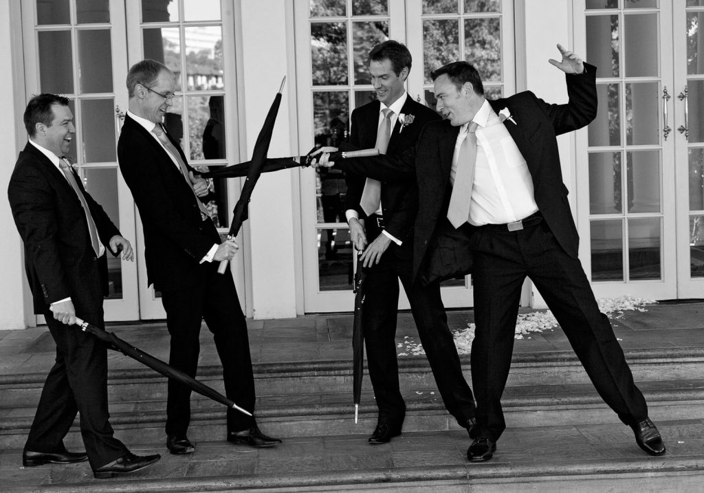 Grooms men in black suits playing with umbrellas at The Westcliff Hotel in Johannesburg