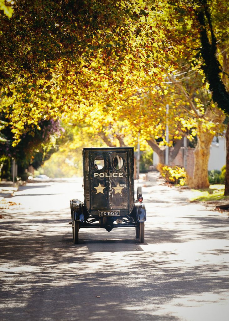 Police car driving under trees with yellow leaves in autumn Johannesburg Parktown