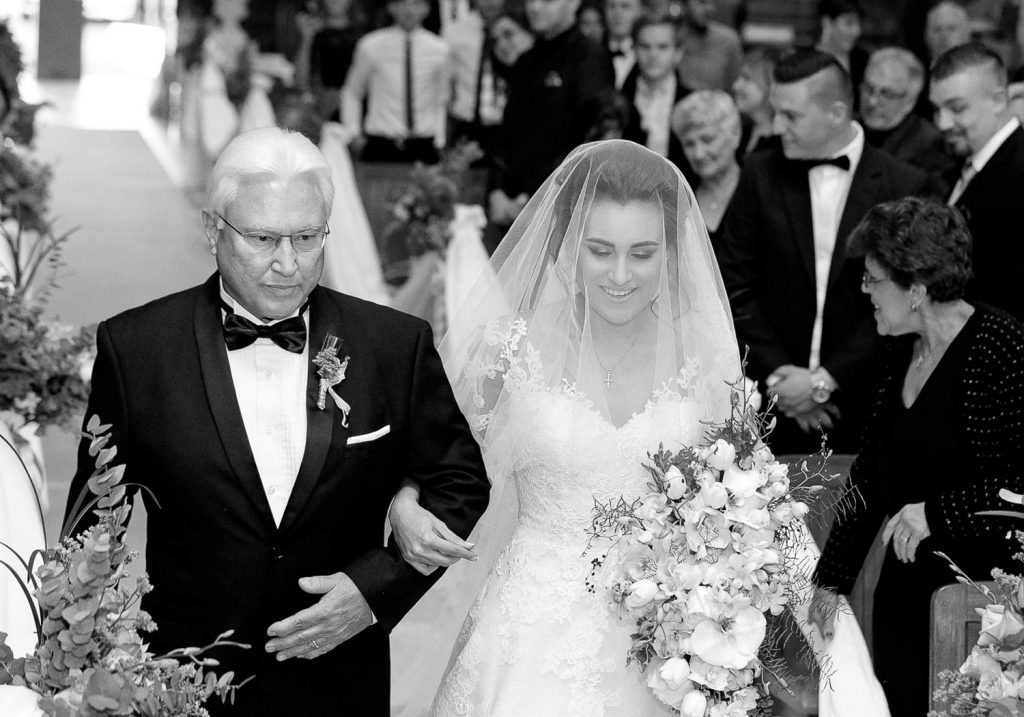 father walking down the bride in the church at Our Lady Of Cedars on Woodmead