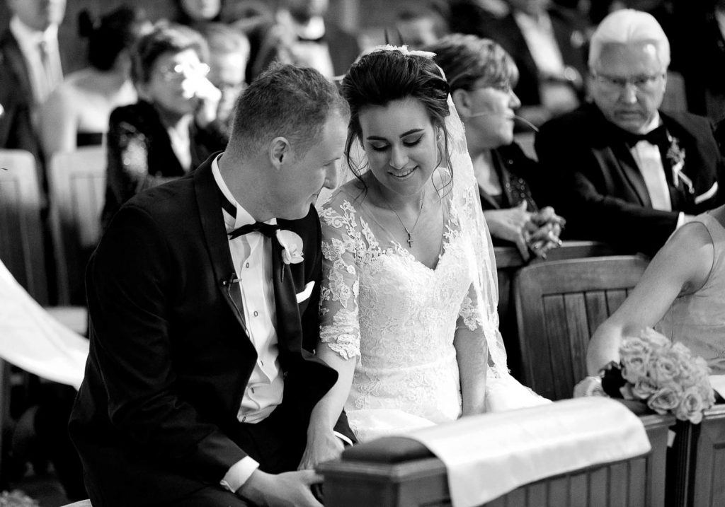 black and white image of the couple in church at Our Lady Of Cedars on Woodmead