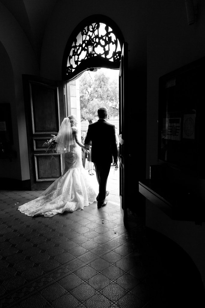 black and white wedding image of the couple walking outside the church door at Die Ooskerk Kirkness Street Clydesdale Pretoria