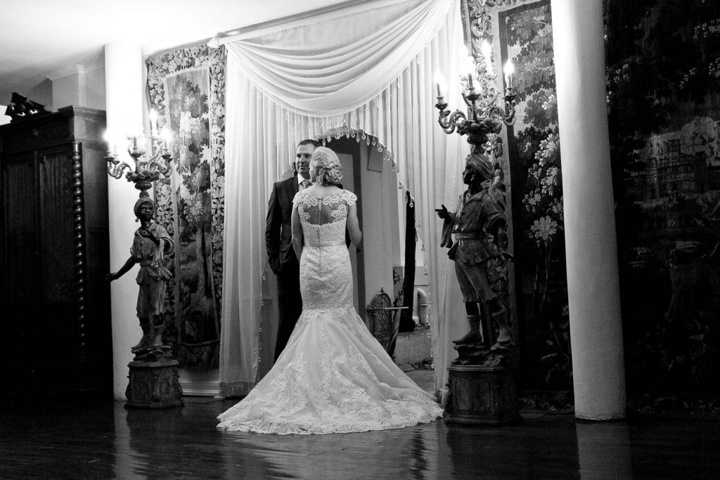 black and white image of bride and groom standing under the curtains at Illyria House in Pretoria