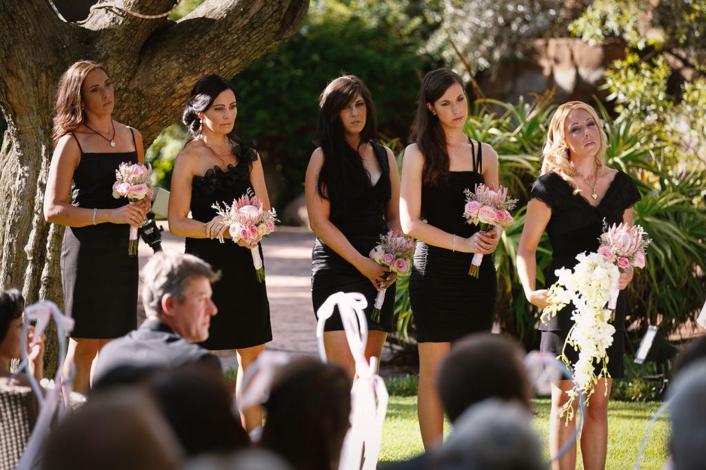 bridesmaids in black dress walking on the grass at Longmeadow Farm Fourways