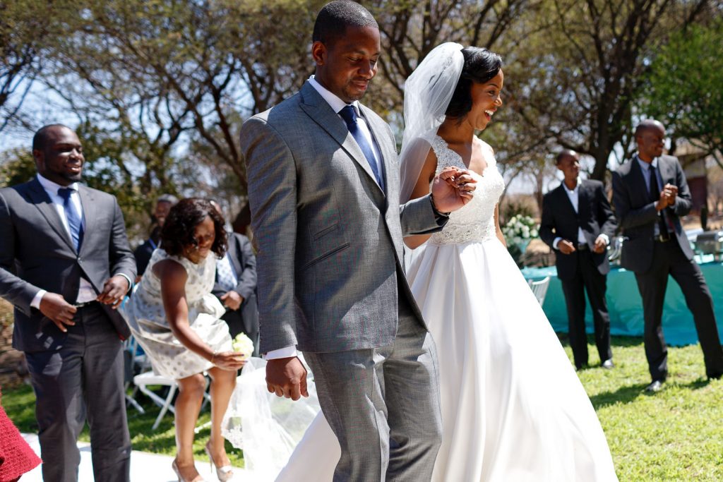 Married couple walking down the aisle at African bride smiling at The Grand Palm Hotel in Gabarone Botswana