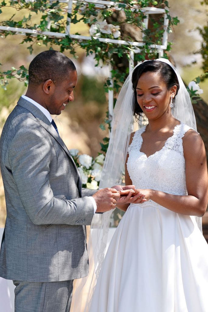 African groom putting on the brides wedding ring in Botswana