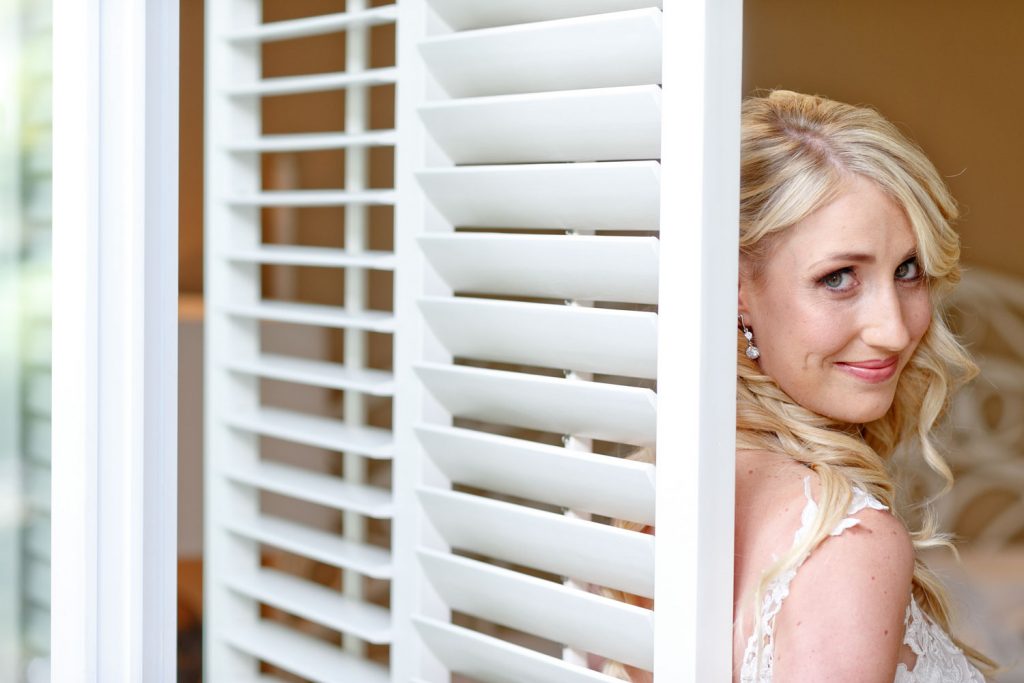 bride standing behind the white shutters at the 12 Apostles Hotel