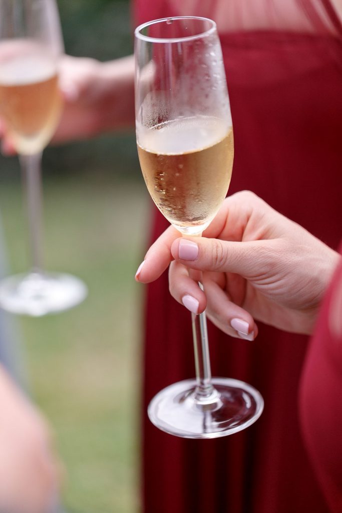 bridesmaid in a red dress holding a champagne glass at 12 Apostles Hotel in Cape Town