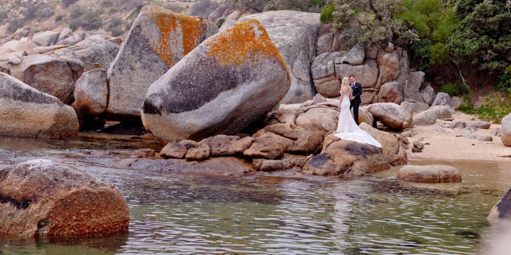 wedding couple standing on a rock