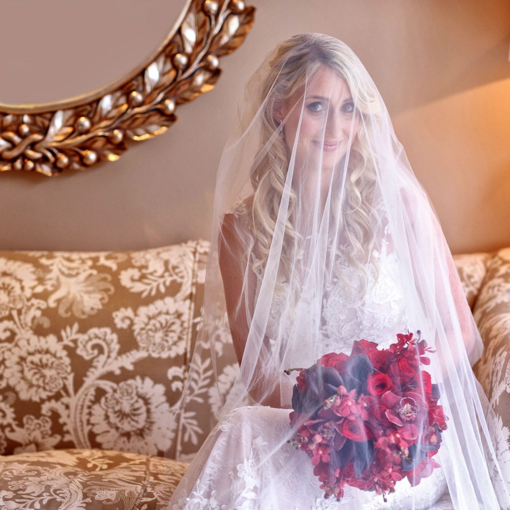 wedding veil hanging over the bride holding a red boutique at 12 Apostles Hotel on the Atlantic Seaboard
