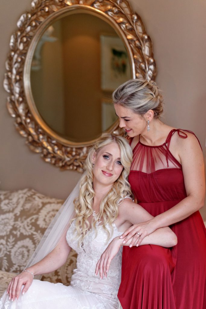 bridesmaid in a red dress hugging the bride at