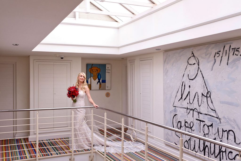 bride in a white dress holding a red boutique at the Twelve Apostles Hotel in Camps Bay