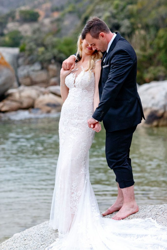 a married couple standing on the rocks at Camps Bay Beach Wedding South Africa