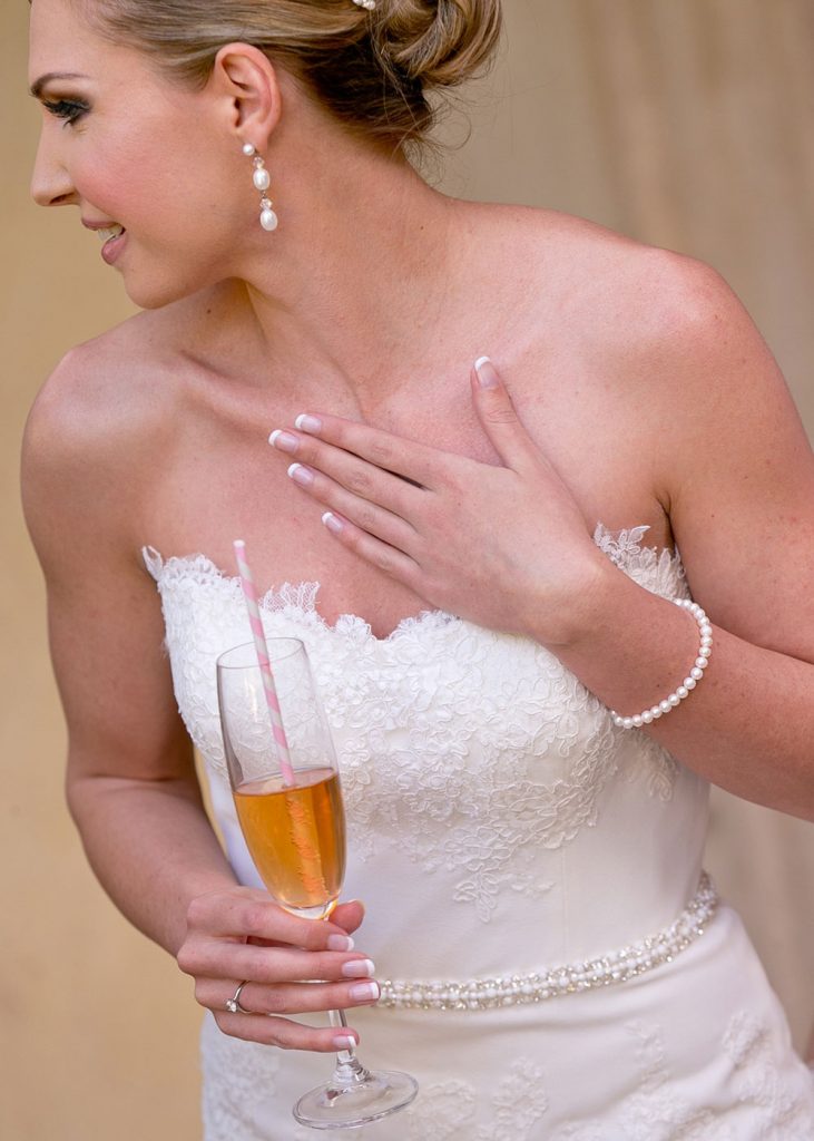 bride holding a champagne glass with a pink and white candy straw Johannesburg bride posing in front of the fountains at The Palazzo Hotel Montecasino
