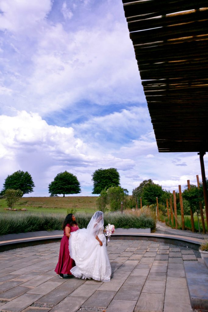 Precious The Wedding Planner helping the bride enter the glass chapel at Groomsmen celebrating on the hill at Brahman Hills in Nottingham Road