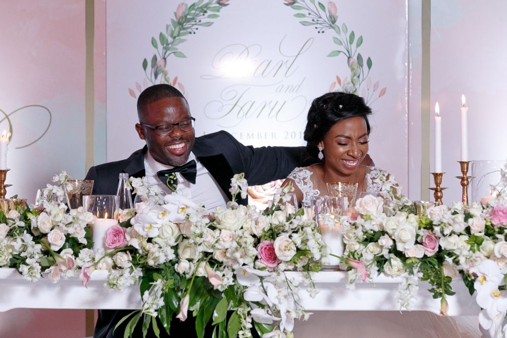 African bride and groom smiling at their wedding reception held in the Glass House