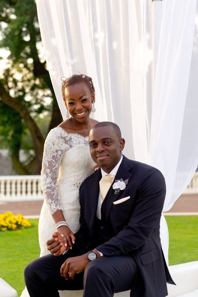 wedding couple sitting under a white canopy