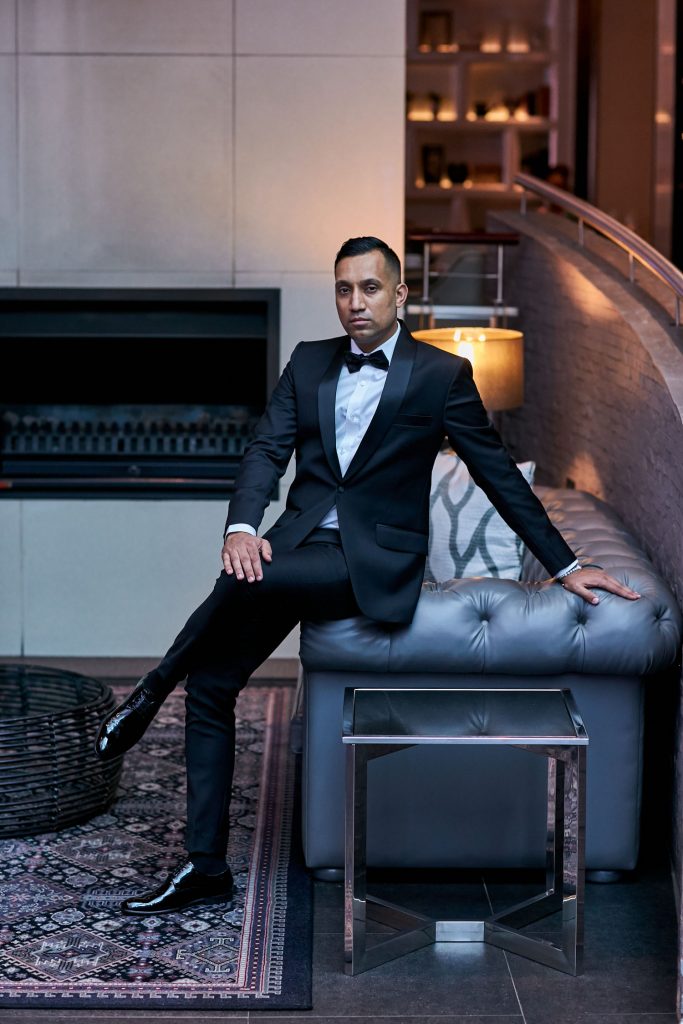 Groom sitting on a grey leather coach at Melrose Arch Hotel in Rosebank