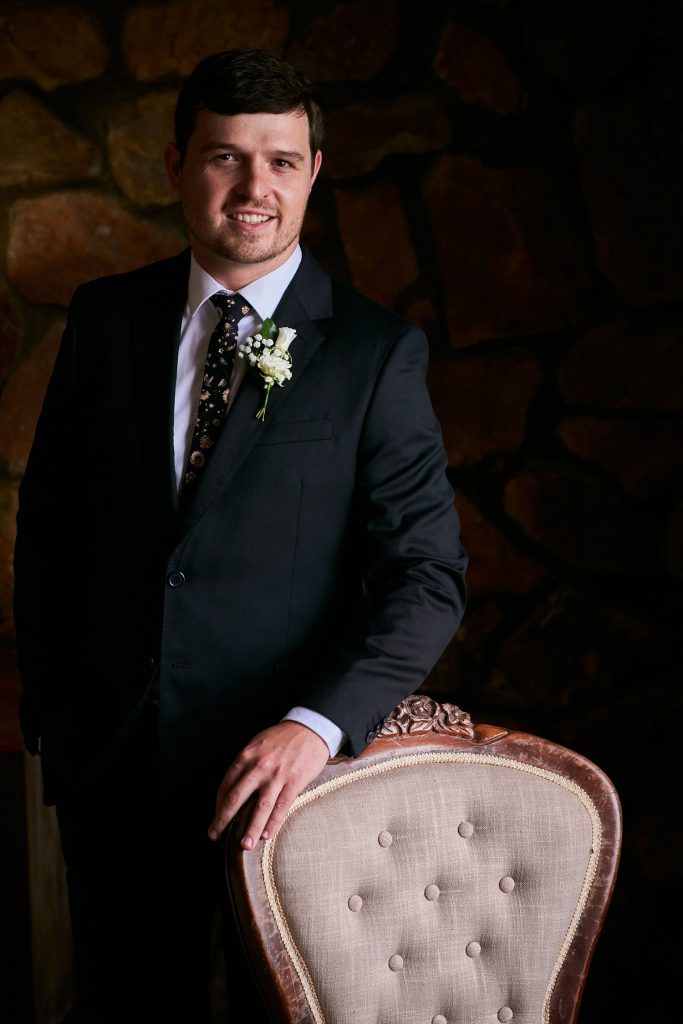 The Groom standing by a Vintage chair at Lezar Opstal Wedding venue