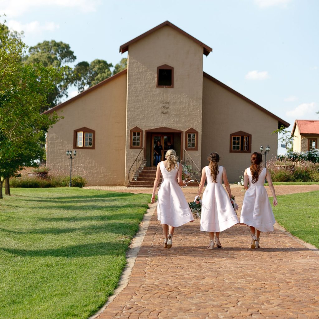 bridesmaids in pink dresses walking to church at Lezar Opstal Wedding Venue