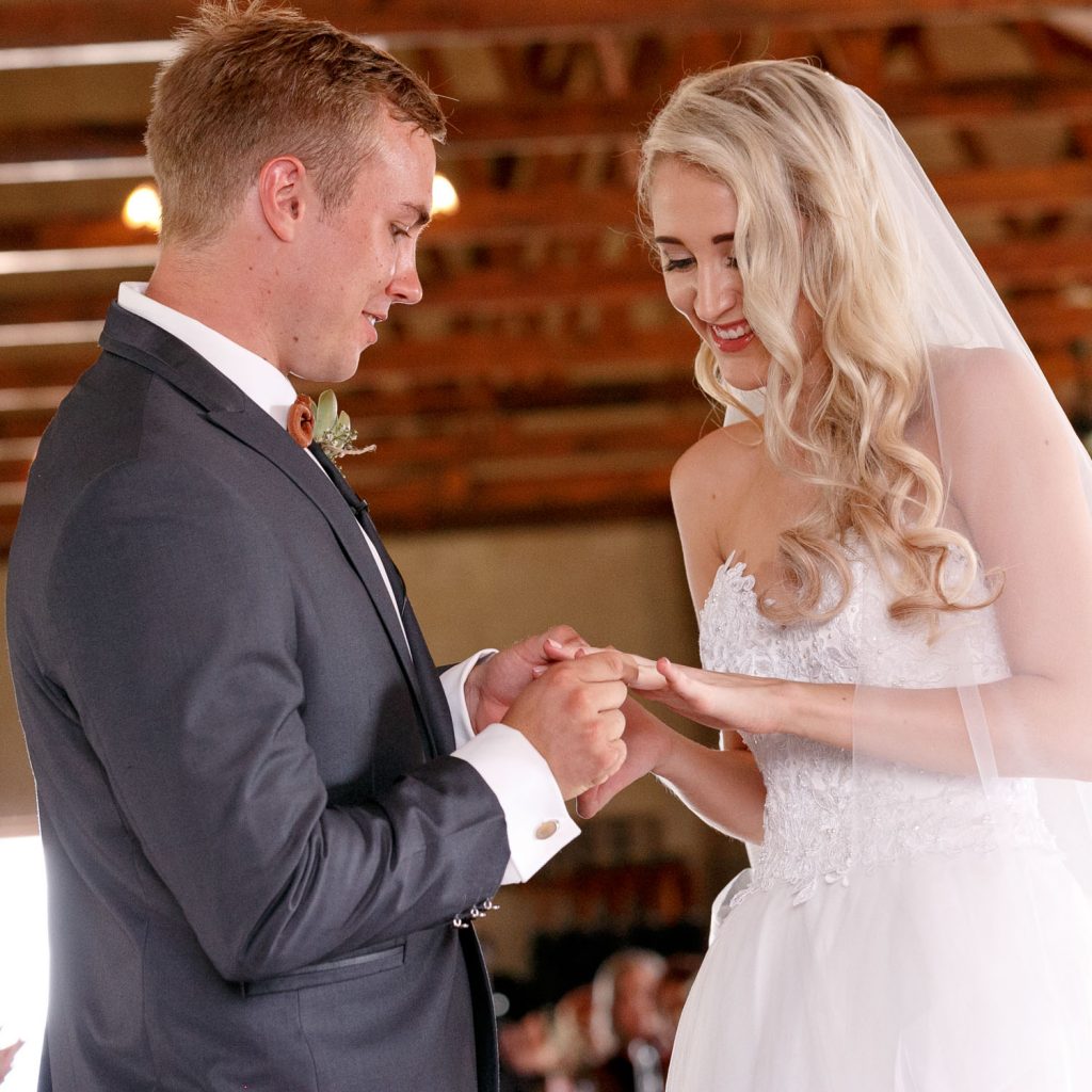 groom slipping on the wedding ring at Lezar Opstal Wedding Venue