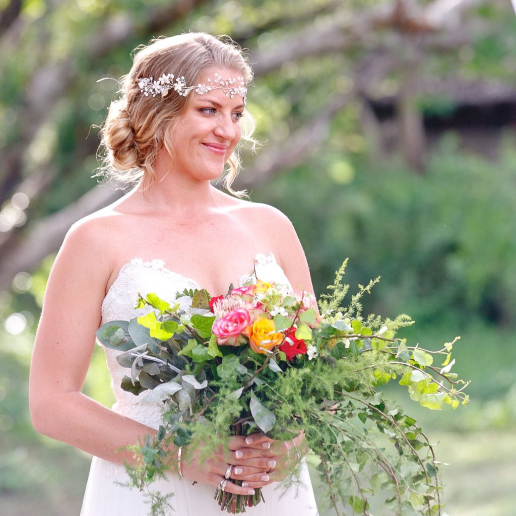 bride holding a pretty pink and orange wedding bouquet at Victoria Falls in Zimbabwe