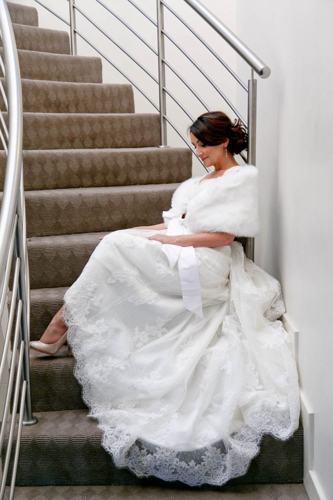 Bride sitting on the stairs at St Andrews Hotel and Spa