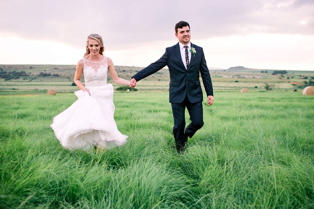 wedding couple walking in the green fields at Lezar Opstal Wedding Venue